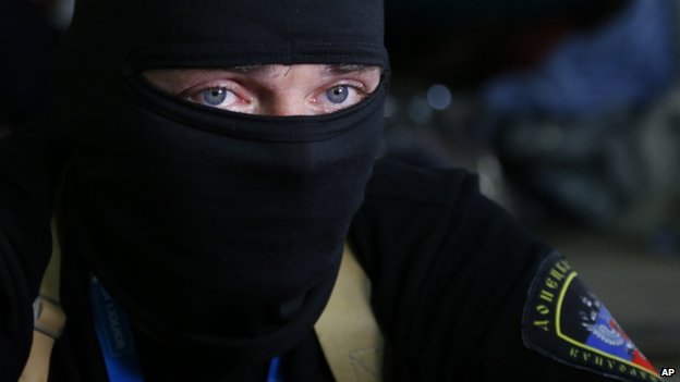 A masked pro-Russian activist guard looks through a window of the regional administration building seized in Donetsk (18 April 2014)<br />Pro-Russian separatists in eastern Ukraine have refused to leave official buildings despite the Geneva deal