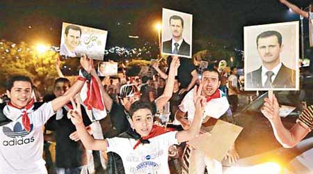 敍利亞民眾高舉阿薩德的肖像慶祝。