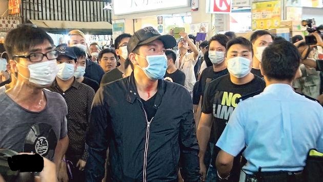 銅鑼灣佔領現場昨傍晚突然有一批戴口罩的男子出現，在記利佐治街把佔領者的鐵欄路障搬開，與佔領者推撞，雙方衝突，有口罩男頸上染上血漬（中）。