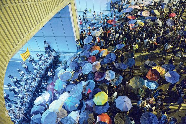 大批佔中示威者昨晚舉起雨傘湧入特首辦外的龍和道隧道，數十名防暴警察一度站在隧道口前築起防線，並舉起黃旗警告，但示威者人數太多，警察終於撤退回特首辦。